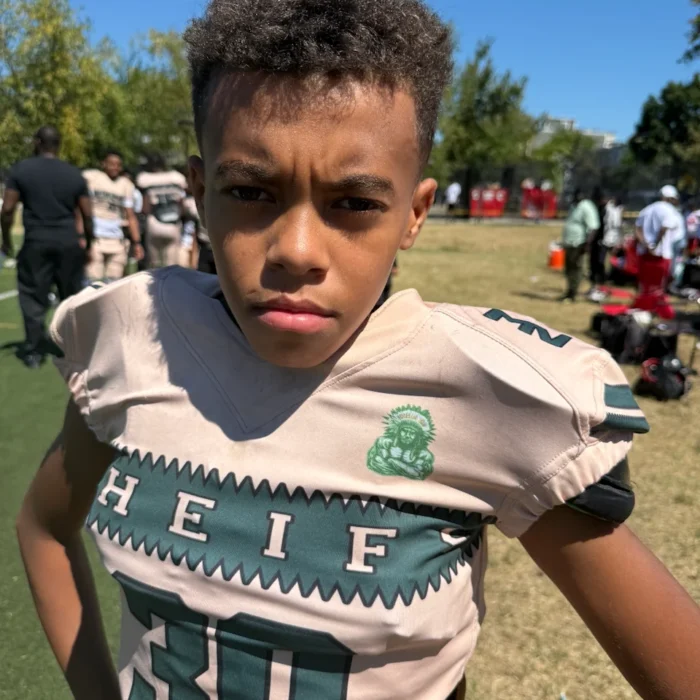Young CBL football player in pads on the sideline