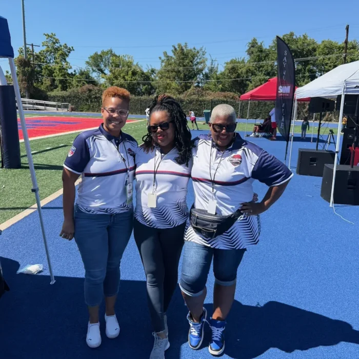 Three CBL volunteers in league polos on the blue turf