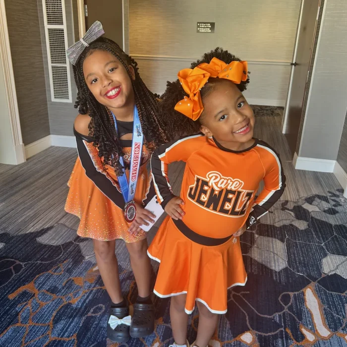 Two young Rare Jewelz cheerleaders, one wearing a championship medal