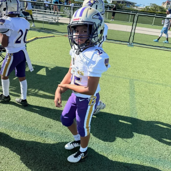Young WBUR Ravens player in uniform on the turf before kickoff
