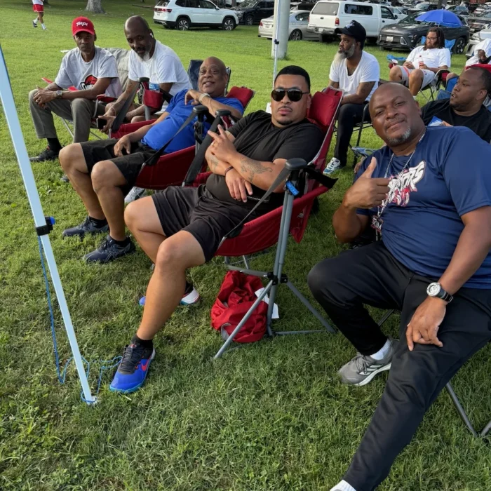 Coaches and parents watching the game from under the sideline tent