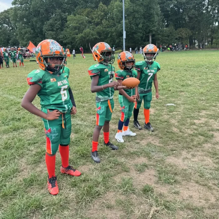 Young football players in green and orange lined up on the field